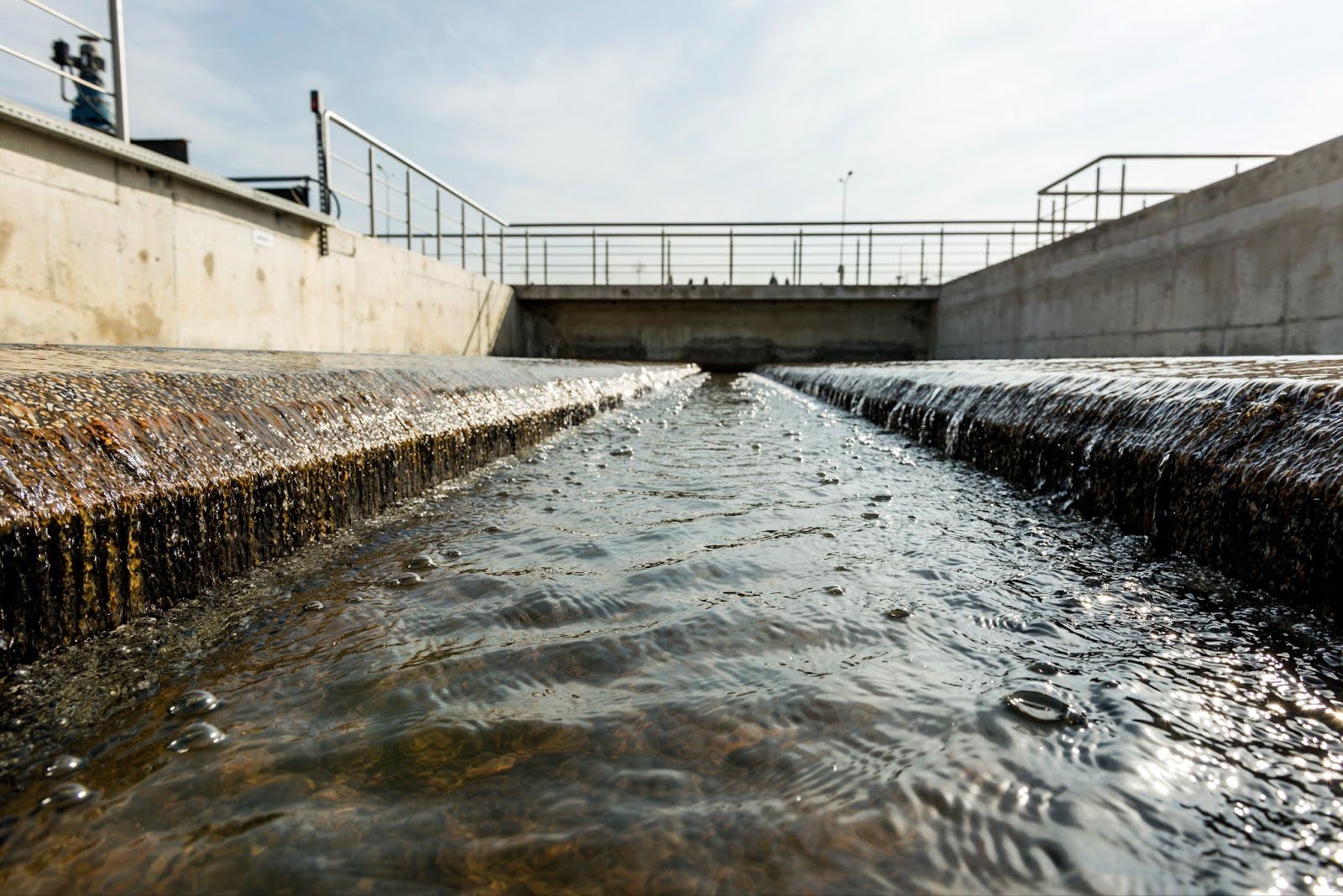 low-angle view of clear water flowing through a concrete channel at a water treatment facility.